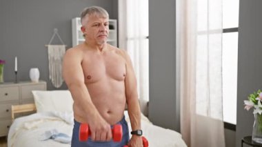 Üst düzey bir adam modern bir yatak odasında halterlerle egzersiz yapıyor, yaşlı yetişkinlerin sağlığını ve fitnesini destekliyor..