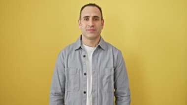 Gözleri kapalı ve kolları havada neşeli, genç İspanyol adam sarı izole arka plandaki başarısını kutluyor. Gömlek giyen. 