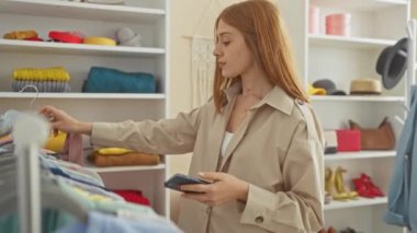 İyi organize edilmiş bir gardıropta giysileri karıştıran genç bir kadın elinde bir akıllı telefon ve pembe bluzlu bir askıyla.
