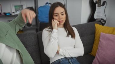 Bir erkek, samimi bir oturma odasında endişeli bir kadını sevgiyle rahatlatır.