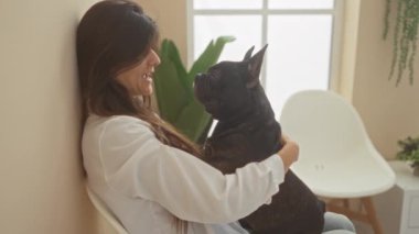 Genç bir İspanyol kadın, modern bir bekleme odasında ya da veteriner kliniğinde elinde bir buldog tutarak evcil hayvan sahibiyle hayvanı arasında güçlü bir bağ olduğunu gösteriyor..