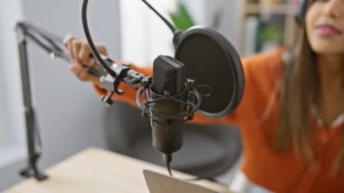 Genç bir İspanyol kadın modern bir radyo stüdyosunda mikrofon ayarlıyor. Yayına ya da kaydına hazır..