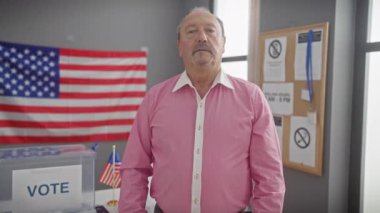 Amerikan bayrağına karşı oy kullanma merkezinde bıyıklı olgun bir adam var.