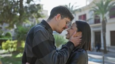 Güneşli bir şehir sokağında sevgi dolu bir çift öpüşür, sevgi, romantizm ve canlı bir şehir atmosferi sergiler..