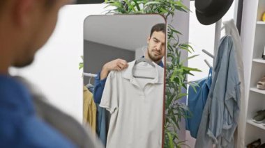 Çekici, genç İspanyol bir adam modern bir soyunma odasında kıyafet seçiyor..