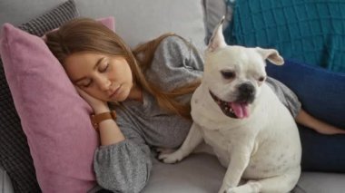 Sarışın, beyaz bir kadın evdeki kanepede uyuyor. Dost canlısı köpeğiyle birlikte..