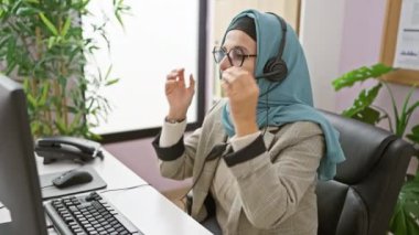 Ofiste tesettürlü orta yaşlı kadın kulaklığı çıkarırken strese girdi.