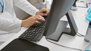 Beyaz laboratuvar önlüklü, parlak bir laboratuvar ortamında bilgisayar üzerinde çalışan odaklanmış bir İspanyol..