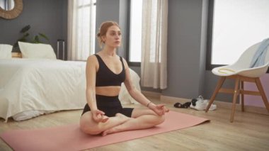 Huzurlu bir kadın rahat bir yatak odasında yoga yapıyor. Sağlığını, huzurunu ve evde sağlıklı bir yaşam tarzını gösteriyor..