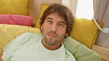 Neşeli, komik suratlı, beyaz adam, dilini yatak odasına sokuyor, neşe dolu. Genç bir yetişkinin eğlenceli, olumlu duygularının ifadesi. Evde pijamalarıyla eğleniyor.!