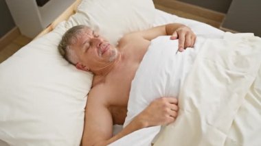 Üst düzey bir adam yatak odasında uyanıp esniyor, evde yenilenmiş bir sabah rutinini canlandırıyor..