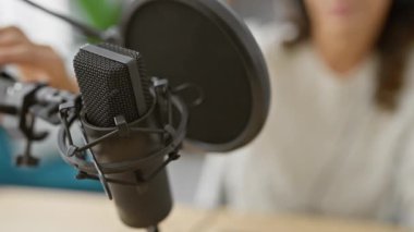 Bir yayın stüdyosunda mikrofona konuşan kulaklıklı, olgun İspanyol bir kadın.