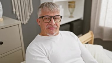 Gri saçlı neşeli orta yaşlı bir adam, rahat yatak odasındaki 'ampul' anında kafasını işaret ediyor, pijamalarıyla gülümsüyor, imrenilecek hafızası olan harika bir fikri anımsıyor.!