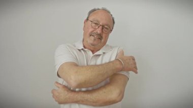 Kel, orta yaşlı, bıyıklı ve gözlüklü, kendini seven bir adam. Ayakta duruyor, sarılıyor ve gülümsüyor; kendinden emin ve mutlu, izole beyaz bir arka planda..