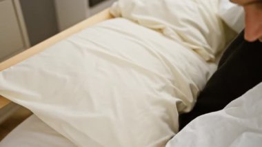 Tarafsız yatak odası ve yumuşak yastıklarla huzurlu bir şekilde uykuya dalan bir adam..