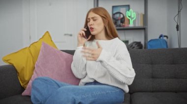 Genç bir kadın koltukta otururken telefonla konuşuyor, evdeki çevresiyle ilgili endişelerini dile getiriyor..