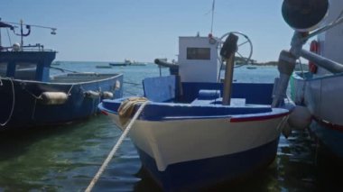 Porto sezareo, İtalya, Puglia 'nın durgun sularına yanaşmış mavi ve beyaz balıkçı tekneleri, berrak bir gökyüzü zeminiyle Salento' da deniz kenarında yaşam ve kültür sergiliyorlar..