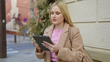 Şehir caddesinde tablet kullanan sarışın kadın modern şehir yaşam tarzını ve teknolojisini yansıtıyor..