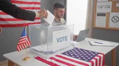 İyi aydınlatılmış bir seçim merkezinde, bir kadın oy pusulasını erkek gözlemci olarak kullanır, Amerika 'da demokrasiyi sembolize eden Amerikan bayrakları.