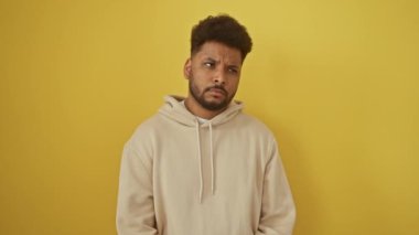 Neşeli Afro-Amerikalı adam, sarı kapüşonlu ve heyecan saçan, bir numaralı başarı fikrini sergiliyor - şevkle sarı izole edilmiş bir arka plana işaret ediyor.