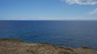 Torre Dell 'orso' nun bu dingin deniz manzarası İtalya 'nın Puglia şehrinde ufka doğru uzanan engin mavi okyanusu parçalı bulutlu bir gökyüzünün altında yakalıyor..