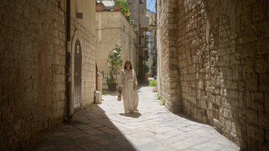 Güzel genç bir kadın, Bari 'nin Puglia, İtalya' daki eski kasabasının büyüleyici taş sokaklarında yürüyor, gün ışığında banyo yapıyor..