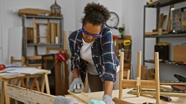 Genç bir kadın, iyi donanımlı bir marangozluk atölyesinde kumdan ağaçlar yapıyor..