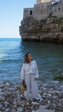 Genç, İspanyol, polignano 'nun kayalık sahillerinde bir kısrak, puglia, İtalya, deniz manzarası ve arka planda tarihi kayalık mimarisi..