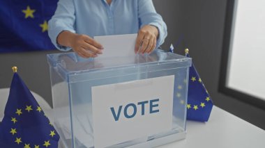 A woman casts her ballot in a european-themed indoor polling station, symbolized by an eu flag and a clear ballot box. clipart