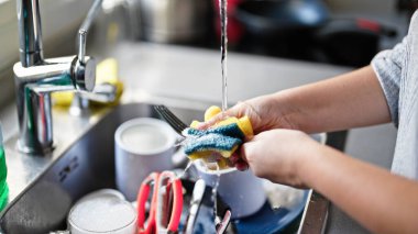 Genç ve güzel İspanyol kadın mutfakta tabak yıkıyor.