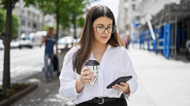 Madrid sokaklarında akıllı telefon kullanarak gülümseyen güzel İspanyol kadın.