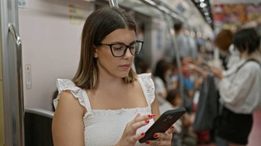 Güzel İspanyol kadın akıllı telefonunu kullanmak için boş bir metrodan faydalanıyor.