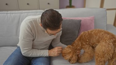 Orta yaşlı bir adam modern bir dairenin rahat oturma odasında kaniş besliyor..
