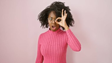 Afro-Amerikalı bir kadın pembe süveter içinde arka planda güzel bir jest yapıyor.