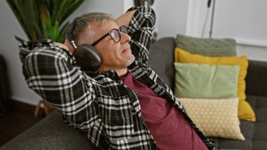 Gri saçlı ve gözlüklü rahat bir son sınıf öğrencisiyim. Kanepede uzanmış, siyah kulaklıklı müziğin keyfini çıkarıyorum..