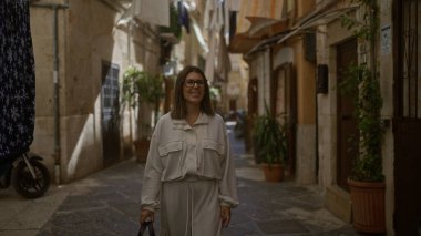 Genç bir İspanyol kadın, Bari 'nin Puglia, İtalya' daki güzel sokaklarında yürüyor. Etrafı büyüleyici yaşlı binalar ve yemyeşil yerlerle çevrili..