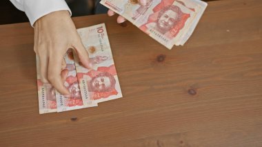 İyi aydınlatılmış bir odanın içindeki ahşap bir masada Kolombiya pezosu sayan birinin elleri..