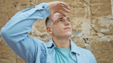 Yakışıklı, genç, İspanyol bir adam. Şehir sokağındaki güneşten korunuyor..