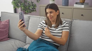 Gülümseyen kadın modern dairede selfie çekiyor.