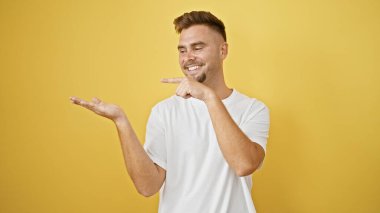 Yakışıklı İspanyol adam gülümsüyor ve sarı arka planda beyaz gömleği gösteriyor.