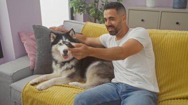 Kapalı alanda sarı bir kanepede oturan köpekli yakışıklı İspanyol..