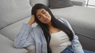 Güzel, esmer, genç bir İspanyol kadın rahat bir kanepede rahat bir şekilde dinleniyor..