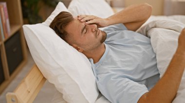 Sakallı genç bir İspanyol hasta ya da üzgün görünüyor. Yatak odasında, alnında, içeride yatarken..