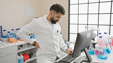 Yakışıklı sakallı adam laboratuarda acı çekiyor.