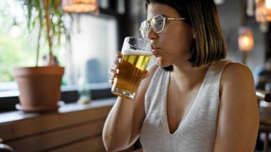 Genç ve güzel İspanyol kadın restoranda bira içiyor.