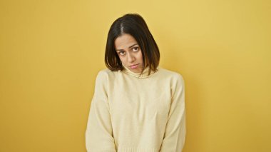 Tarafsız bir yüzü olan, sarı arka planda süveter giyen İspanyol bir kadının portresi..