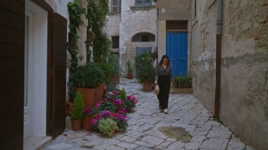 Genç, güzel, İspanyol bir kadın polignano 'nun çiçek desenli sokaklarında yürüyor. Puglia, İtalya' da bir kısrak. Çekici Avrupa mimarisi..