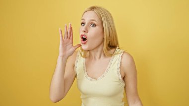 Şaşırmış, sarı saçlı, parlak sarı bir arka planda bağıran genç bir kadın..