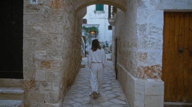 Genç bir İspanyol kadın polignano 'nun taş döşeli caddelerinde yürüyor. Puglia, İtalya' da bir kısrak. Geleneksel Avrupa mimarisini gözler önüne seriyor..