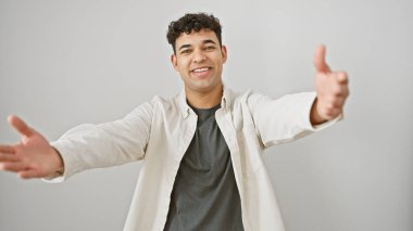 Hoş bir gülümsemesi olan genç, yakışıklı bir adam kollarını beyaz bir arka plana doğru uzatıyor..